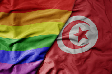 big waving realistic national colorful flag of tunisia and rainbow gay pride flag .