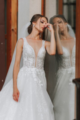 Naklejka premium the bride in a wedding dress with a long train and a veil stands near a glass case. Front photo