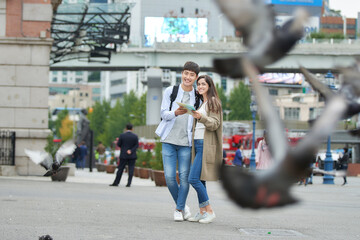 During the trip, a college student couple is looking for their way with a map at Seoul Station during the day.