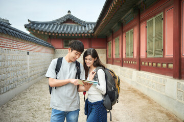 Fototapeta na wymiar A college student couple looking for their way through a map during a trip to a traditional Korean house