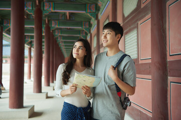 A college student couple looking for their way through a map during a trip to a traditional Korean house