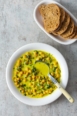 Healthy tasty lunch, soup with chickpeas and spinach, with spices and fresh herbs, with coconut milk, top view