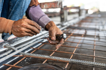 Reinforced concrete structures. Construction worker uses pilers tools and steel tying wire to fasten steel rods of concrete wall at Heavy Industry Manufacturing Factory. Prefabricated concrete walls