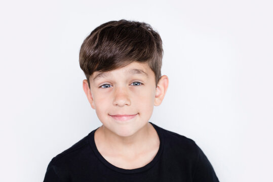 Portrait of a cute innocent boy schoolboy 8 years old, the boy smiles in a black t-shirt on a light background, he is happy that parents love him and accept him as he is