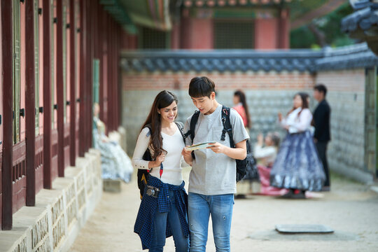 A college student couple looking for their way through a map during a trip to a traditional Korean house