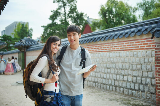 A college student couple looking for their way through a map during a trip to a traditional Korean house