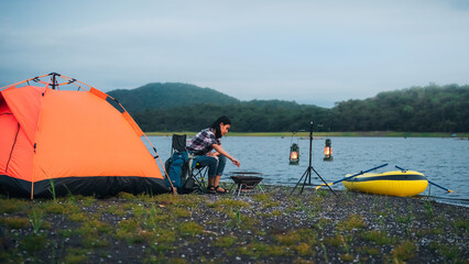 traveler, beautiful asian traveler Camp by the river, with luggage, bonfires and kayaks. Evening camping activities The atmosphere of camping in the evening of Asian women