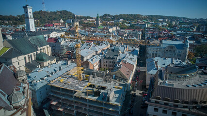 Fototapeta premium The yellow construction crane is working. View from above. Lviv, Ukraine