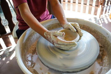 top view of kid making ceramic pot on pottery wheel  