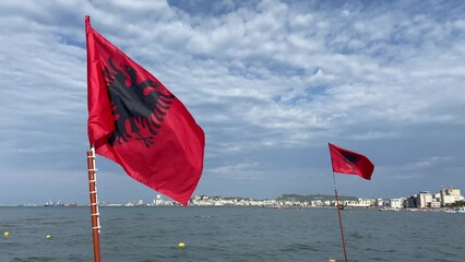 The red silk Albania Flag waves on blue sky background,  flag on a flagpole