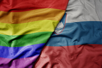 big waving realistic national colorful flag of slovenia and rainbow gay pride flag .