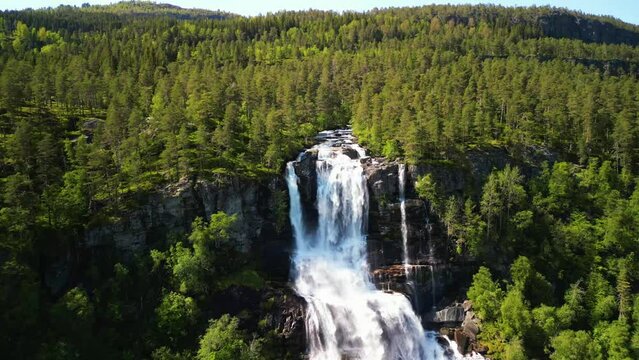 Drone view over Tvindefossen waterfall with green lush forest view on a sunny day