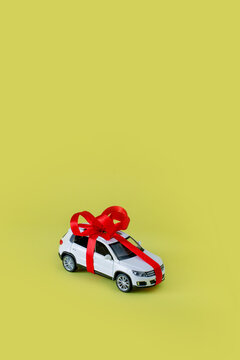 White model car with bow on a yellow background. Car as gift, surprise