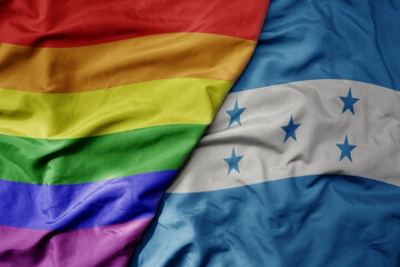 big waving realistic national colorful flag of honduras and rainbow gay pride flag .