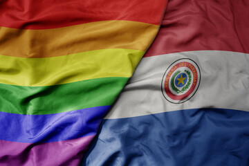 big waving realistic national colorful flag of paraguay and rainbow gay pride flag .