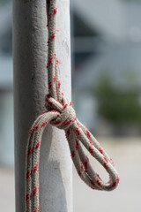 Naklejka premium knotted rope hanging from an old painted pole outdoors (abstract background)