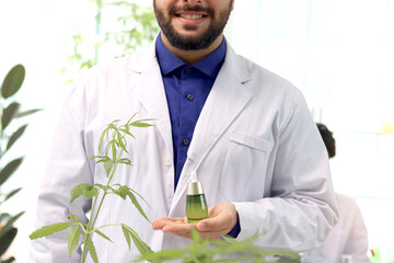 Scientist man holding marijuana oil in laboratory, biochemist doing experiment with hemp leaf,...