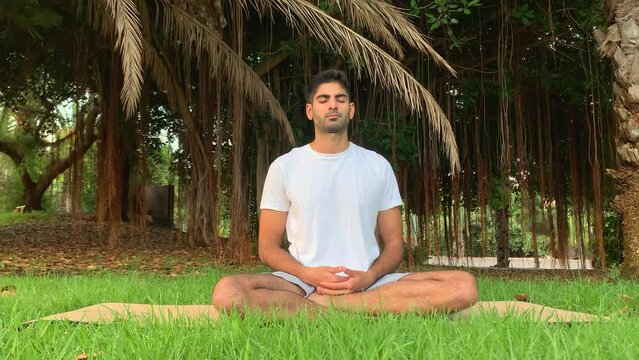 Joven indio practicando t&eacute;cnicas de respiraci&oacute;n. Sesi&oacute;n sobre colchoneta de yoga en el parque. Relax al aire libre para una mejor salud. Ejercicios de enfoque por la ma&ntilde;ana en verano en Tenerife