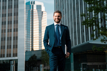 Happy business man wearing suit jacket. Portrait of a mature businessman. Businessman walking. Businessman in front of office. Handsome businessman. Business portrait of serious business man outdoor.