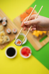 female hand holding chopsticks roll against the background of a set of rollers 9