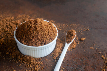 Muscovado brown sugar in white ceramic bowl on rusty table  background.