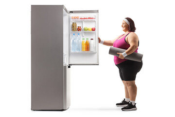 Fototapeta na wymiar Overweight woman in sportswear opening a fridge with food