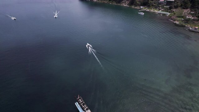 Drone view over boats driving in a sea by the coast with forested vegetation