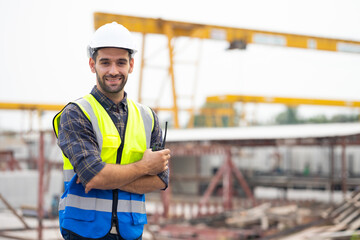 Portrait building and construction worker, Hiapanic latin male wearing safety hard hat helmet standing with arms crossed at construction site and looking at camera