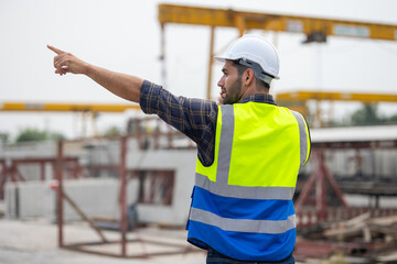 radio transmitter. Hispanic latin architect construction Engineering man in hardhat talking on walkie talkie at factory facilities. Heavy Industry Manufacturing Factory. Prefabricated concrete walls