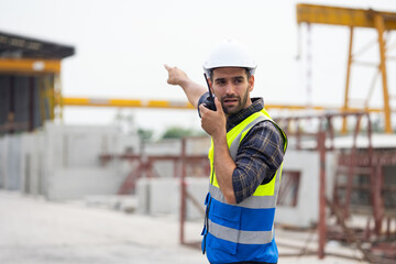 radio transmitter. Hispanic latin architect construction Engineering man in hardhat talking on walkie talkie at factory facilities. Heavy Industry Manufacturing Factory. Prefabricated concrete walls