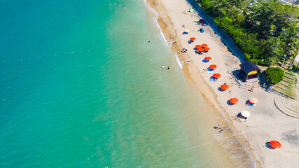 Aerial view of a beach with colorful umbrellas scattered and people on a sunny day