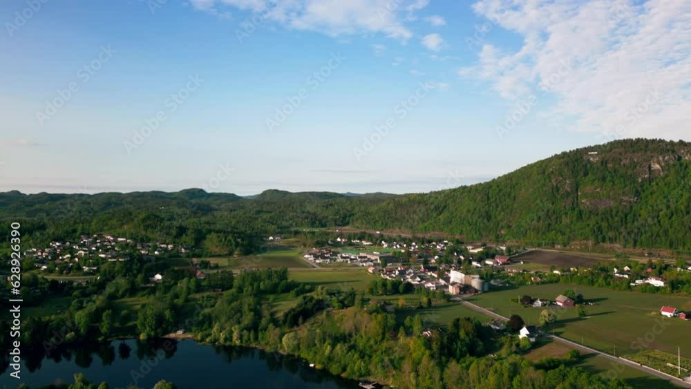 Poster Landscape aerial footage over rural countryside houses on lawns and a river with hills in Norway