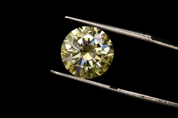 Closeup of tweezers holding a piece of diamond isolated on a black background