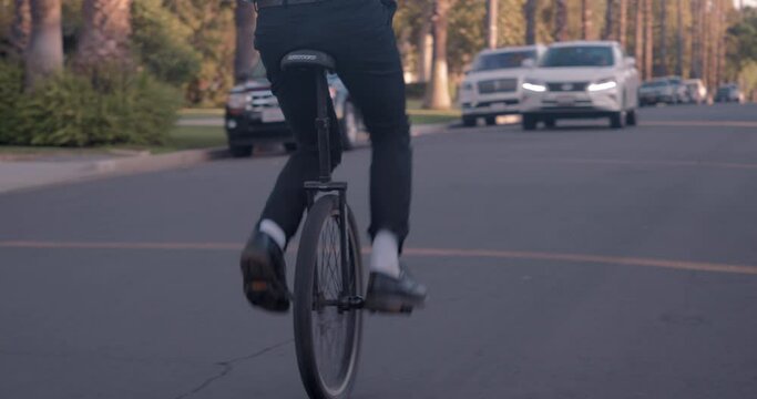 Man Riding Unicycle Through Neighborhood