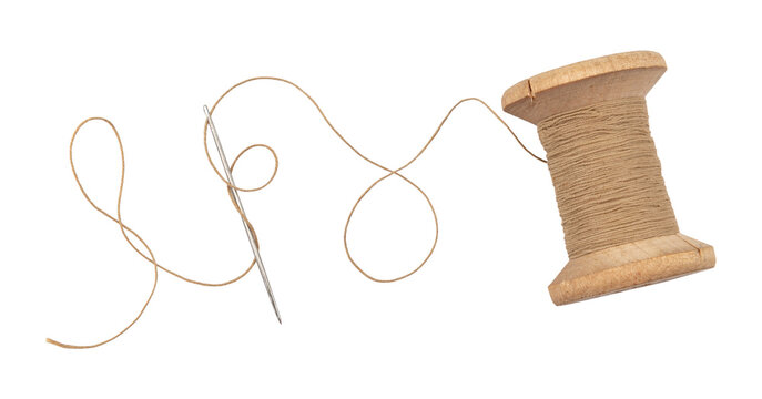 Old wooden spool of thread and needle on a white background. Sewing accessories
