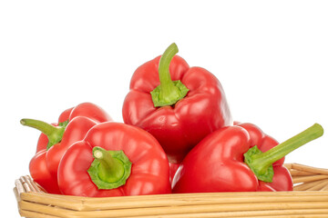 Several red bell peppers with straw tray, macro, isolated on white background.