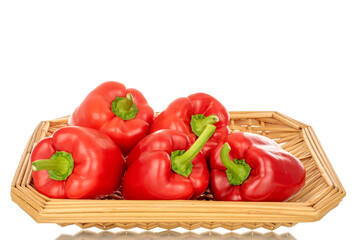 Several red bell peppers with straw tray, macro, isolated on white background.