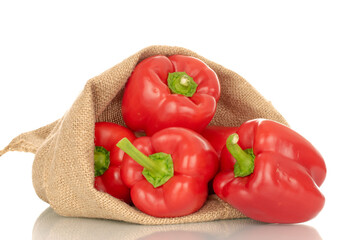 Several red bell peppers in a jute sack, macro, isolated on white background.