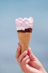 hand holding strawberry ice cream cone 