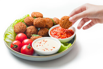 Hand holding a bowl of falafel, hummus and fresh salad. White background. Traditional arabic, eastern or israeli food