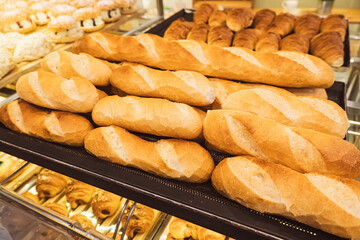 Freshly baked bread on bakery shelves. Bread diversity in bright light. Breads with golden crust. Loaves of bread assortment.