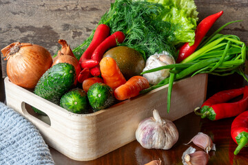 Ripe vegetables, carrot, tomato, garlic, onion lettuce, chili pepper in a light wooden box