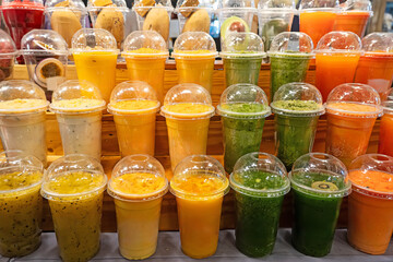 colorful plastic cups with fruit and berry juice at market,