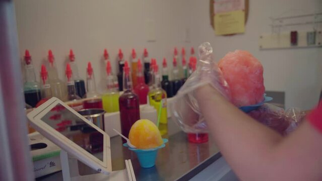 Worker making sweet and tasty shaved ice at the store with fruity syrups