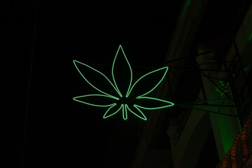 Neon sign on a brick wall in shape of a simplified weed leaf