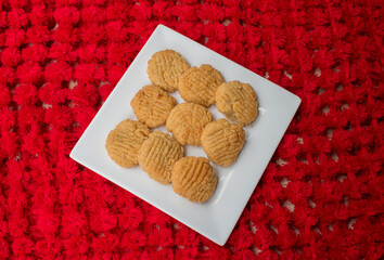 Thekua , an Indian sweet dish or snack in white plate with beautiful red background. Popular in...