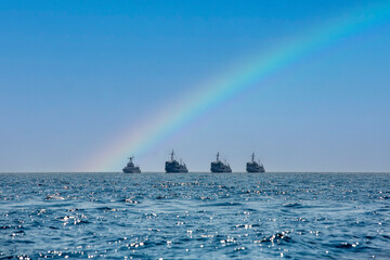 Warships at sea with a rainbow in the sky