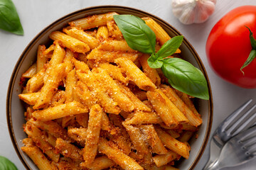 Homemade Tomato Pesto Pasta with Cheese and Basil in a Bowl, top view. Flat lay, overhead, from above. Close-up.