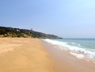 Faro de Camarinal, Leuchtturm auf einer Klippe und der wunderschöne Sandstrand mit dem türkisblauen Atlantik, Playa Los Alemanes, Costa de la Luz, Atlanterra, Andalusien, Spanien