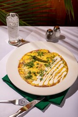 Appetizing omelette with fresh vegetables and herbs on a white plate, ready to be enjoyed